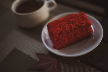 Red beautiful cake with a Cup of coffee and an autumn leaf.