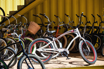 a lot of colored bikes model chopper in the city next to the yellow building in summer