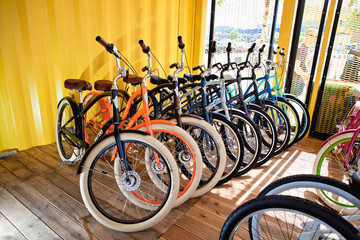 a lot of colored bikes model chopper in the city next to the yellow building in summer