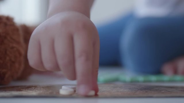 Kid plays with scattering medicine drugs. Toddler touches pills without parent control. Dangerous situation.
