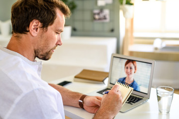 Man having video call with doctor on laptop at home, online consultation concept.