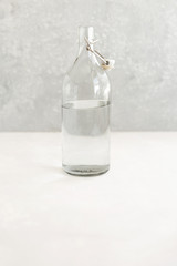 Glass water bottle on a light background, a glass of water with lemon, the concept of a healthy lifestyle and a healthy diet, eco storage,