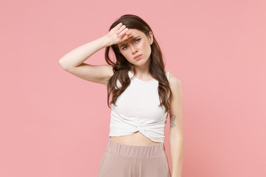 Displeased tired young brunette woman girl in light casual clothes posing isolated on pastel pink background studio portrait. People emotions lifestyle concept. Mock up copy space. Put hand on head.