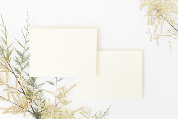 Mockup of white papers and envelope with Tropical palm leaf on gray background, and text space at center. Top view flatlay.