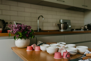Variety of cupcake liners in different colors with a muffin pan and wire whisk