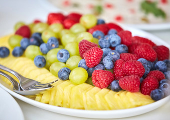 Assorted types of fruit: pineapple, strawberry, grapes, blueberries.