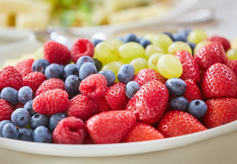 Assorted types of fruit: pineapple, strawberry, grapes, blueberries.