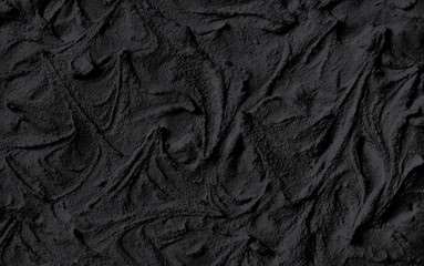 Natural texture liquid cosmetic activated charcoal or volcanic clay for face mask and body. Trendy nursing black wood background.