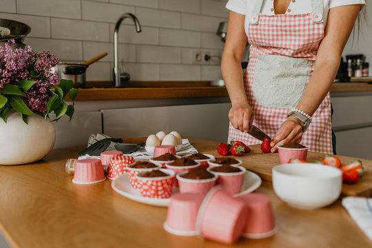 Young woman decorating cupcakes in bright kitchen