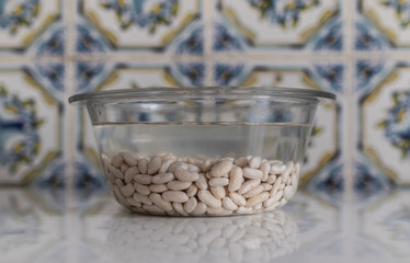 Glass container with white beans to soak. Kitchen with traditional tiles.