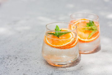 Lemonade, orange cocktail, cold, iced,refreshing summer drink in glasses with slices of orangeand mint. Front view. Selective focus