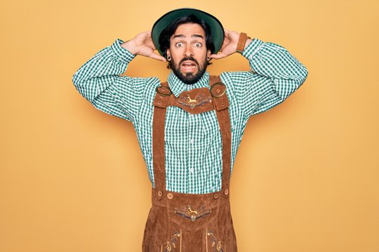 Young handsome man wearing tratidional german octoberfest custome for Germany festival Crazy and scared with hands on head, afraid and surprised of shock with open mouth