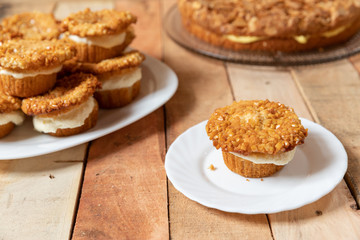 gebackener Bienenstich als Torte und Muffin mit Füllung aus Creme auf Tisch aus Holz