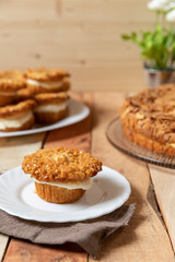 gebackener Bienenstich als Torte und Muffin mit Füllung aus Creme auf Tisch aus Holz