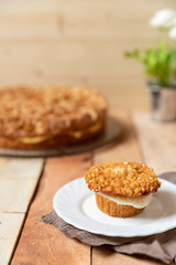 gebackener Bienenstich als Torte und Muffin mit Füllung aus Creme auf Tisch aus Holz