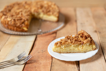 gebackener Bienenstich als Torte mit Füllung aus Creme auf Tisch aus Holz