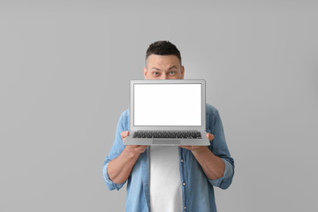 Handsome man with laptop on grey background