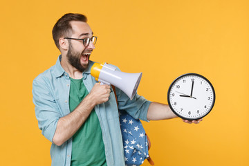 Excited young man student in glasses backpack hold books isolated on yellow background studio....