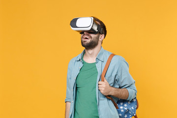 Young man student in casual clothes with backpack isolated on yellow wall background studio portrait. Education in high school university college concept. Mock up copy space. Watching in headset.