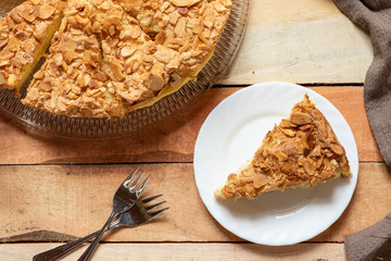 gebackener Bienenstich als Torte mit Füllung aus Creme auf Tisch aus Holz