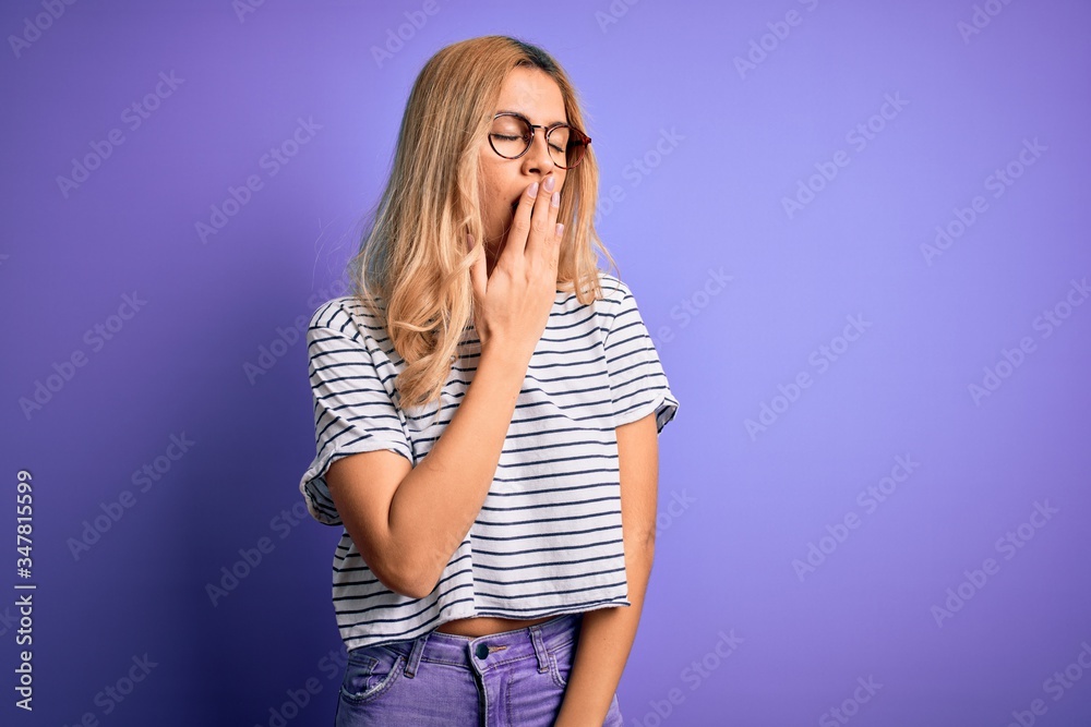 Poster young beautiful blonde woman wearing striped t-shirt and glasses over purple background bored yawnin