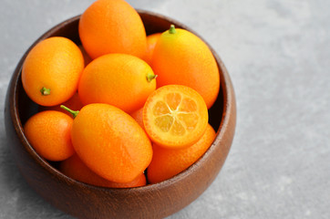 Citrus kumquat fruits in wooden bowl. Healthy vegan food. Kumquat fruit cut in half.