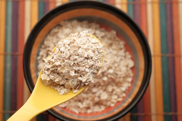 Close up of oats flakes on spoon on table 