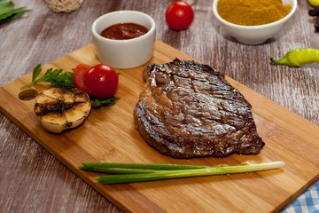 steak with vegetables on a wooden background