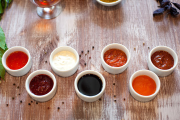 Fototapeta na wymiar assorted sauces in white bowls on a wooden background