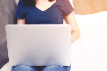 Naklejka premium laptop. lifestyle woman close up hand keyboard sit on the bedroom a using a notebook computer to work from home and search information social network online. wfh.