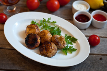 grilled mushrooms on a white plate. Wooden background