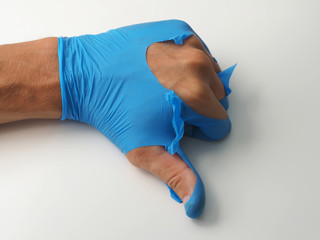 Medical torn glove in hand on white background. Gesture thumb down..