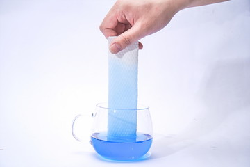 Pick up a paper towel in one hand and place it in the blue test liquid to test its water absorption