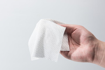 A paper towel is held in one hand for thickness testing against a white background.
