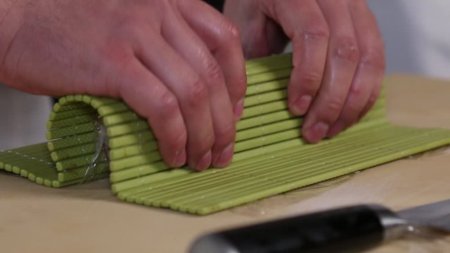 Chef's hands rolling a sushi roll. Sushi making process. Rolls the sushi roll	
