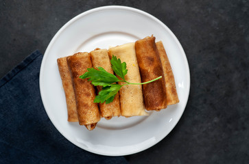 pancakes with meat on a white plate on a stone background