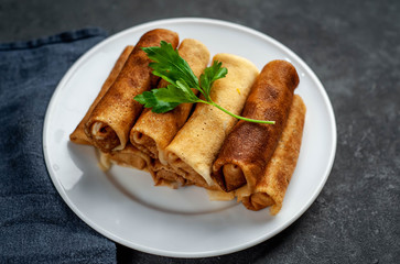 pancakes with meat on a white plate on a stone background