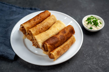 pancakes with meat on a white plate on a stone background