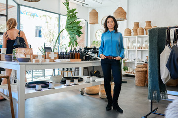 Young Asian entrepreneur standing by a table in her store