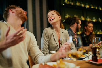 Group of friends sitting in restaurant, eating, laughing and having fun.