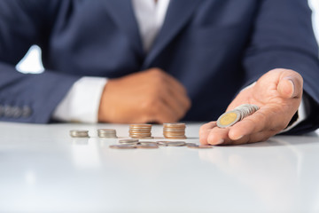 
Businessman hand with putting money coins in the office
concept: Saving money wealth and financial Personal, finance management  loan for a home,
 diagram chart earnings to plan profit
