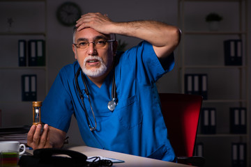 Aged male doctor in the hospital at night