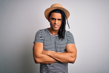 Young african american man with dreadlocks on vacation wearing striped t-shirt and hat skeptic and nervous, disapproving expression on face with crossed arms. Negative person.