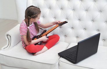  Online lessons of playing guitar at home using laptop. Home education concept.