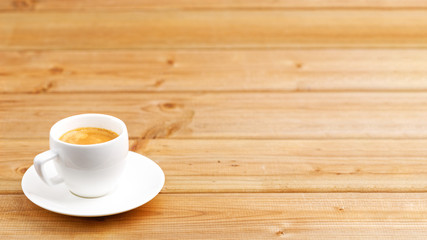 White cup of coffee espresso on wooden background. Shallow focus. Angle view with copyspace.