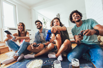 Happy group of young friends playing video games at home. © Mediteraneo