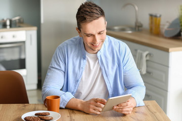 Handsome man with tablet computer in kitchen at home