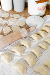 Raw uncooked homemade dumplings with potatoes and onions on wooden table in the kitchen.