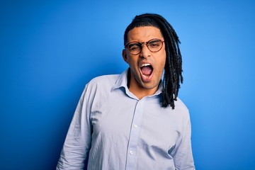 Young handsome african american man with dreadlocks wearing casual shirt and glasses winking looking at the camera with sexy expression, cheerful and happy face.