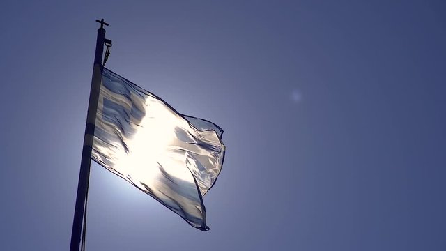 Greek flag proudly waving in front of the sun